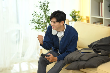 Happy man playing a games on sofa with a joystick on hand