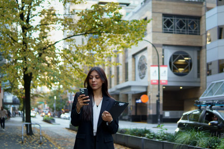 Confident businesswoman checking her smartphone while walking in the city.