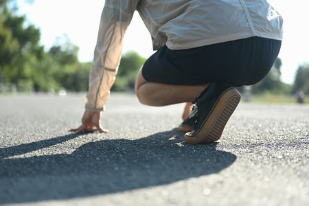 Low angle view of athlete in a starting position on the ground ready to sprint.の写真素材