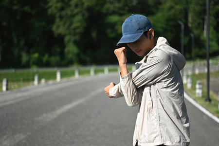 Young sportsman stretching his arms preparing for morning workout in the park.の写真素材