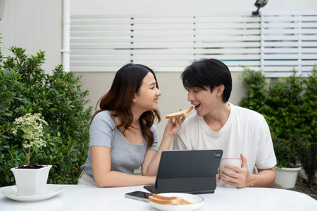 Loving asian couple sharing a breakfast and enjoying relaxed outdoor together.の写真素材