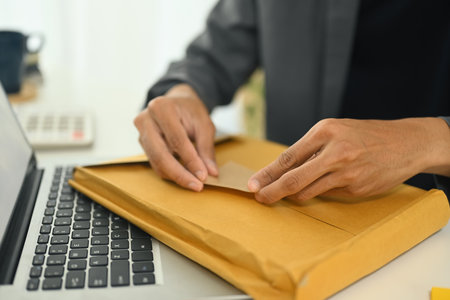 Employee sealing a brown envelope for shipment at desk.の写真素材