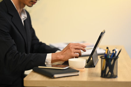 Cropped shot businessman in formalwear managing tasks on digital tablet.の写真素材