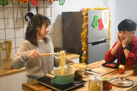 Young happy couple enjoys cooking pasta in kitchen on Christmas eve.の写真素材