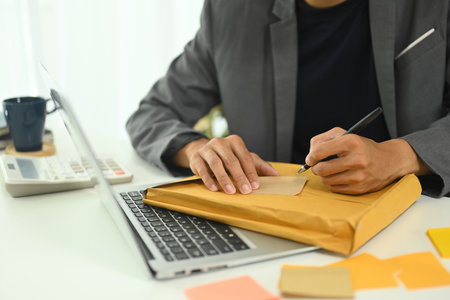Close up male employee writing tasks on adhesive note.