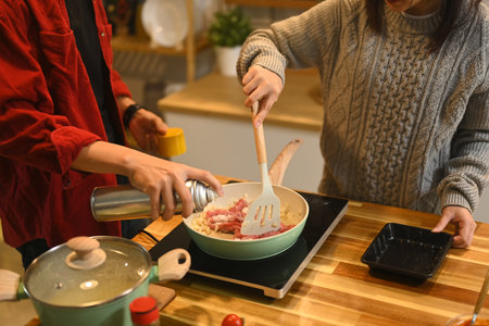 Young couple making pasta sauce for Christmas dinner in a cozy kitchen.の写真素材