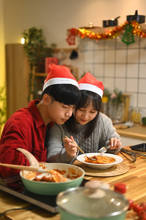 Happy young couple tasting a delicious homemade pasta dish in a kitchen.の写真素材