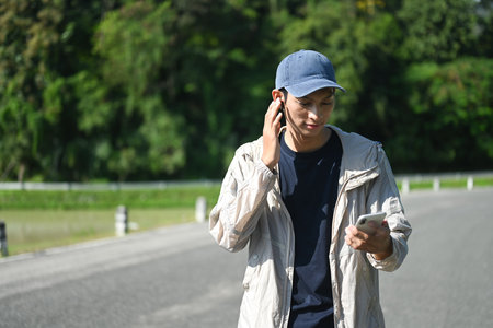 Young male runner checking progress on his smart phone outdoors.
