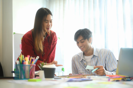 Developer team working on app wireframes at desk with sticky notes and digital prototypes.の写真素材