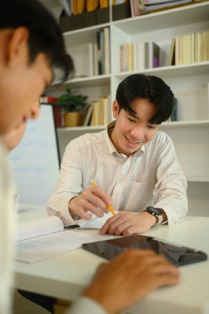 Smiling male tutor guiding student during a personalized study session.の写真素材