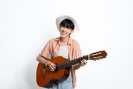 Pretty asian man wearing a straw hat holding a guitar against white background.の写真素材