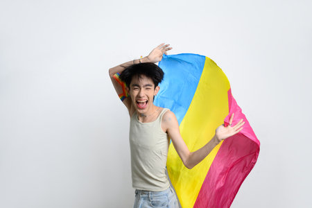 Cheerful individual man waving pansexual pride flag with excitement and joy. LGBTQ pride and equality concept.の写真素材