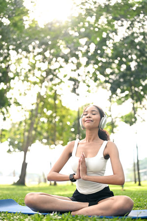 serene young woman wearing headphones and meditating in nature.の写真素材