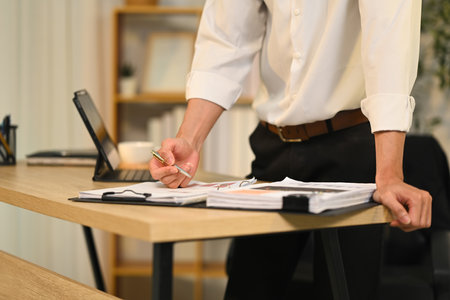 Cropped shot of professional businessman reviewing a stack of documents at office.の写真素材
