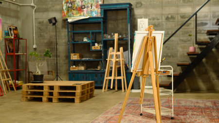 Bright and open art studio with industrial style walls with wooden easels and painting supplies.の写真素材
