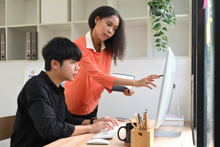 Female employee providing feedback and direction to her colleague during a project discussion.