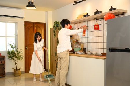 Young adult couple decorating their home with red ornaments for Chinese New Year.