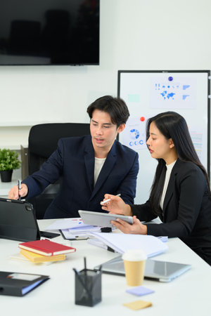 Businesspeople brainstorming and analyzing key business metrics displayed on digital tablet.の写真素材