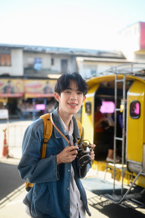 Portrait of young traveler with backpack and vintage camera standing at transportation terminal.の写真素材