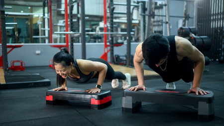Fitness young couple doing push ups on step platforms in the gym.
