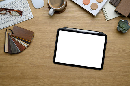 Top view of interior designer workspace with digital tablet, material samples, color swatches and...