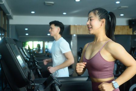 Young sporty woman running on a treadmill at gym. Sports and healthy lifestyle concept.の写真素材
