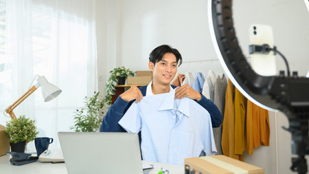 Smiling male business owner presenting shirt during a live stream or product video shoot.