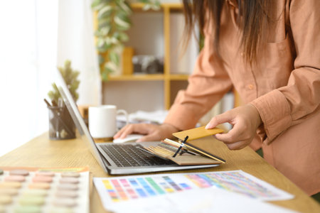 An interior designer working on design project using a laptop displaying a color wheel to choose perfect color combinations..の写真素材