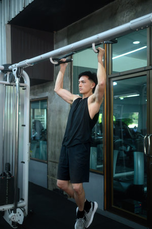 Athlete man doing pull ups on a bar in a modern gym.