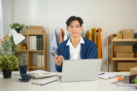 Confident small business owner managing orders and customer interactions on his smartphone.の写真素材