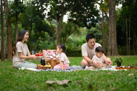 Happy family with two little children enjoying a picnic on a beautiful day in a park.の写真素材
