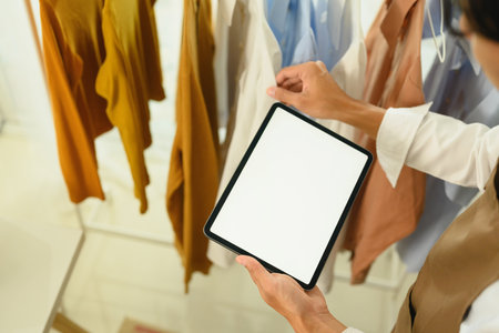 Fashion retailer or small business owner using digital tablet to organize and manage clothing inventory.の写真素材