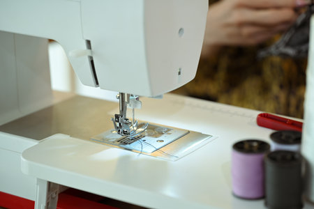 Close up of a sewing machine with thread and fabric at fashion designer workspace.の写真素材