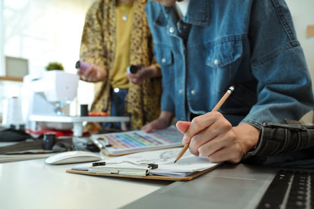 Close up of fashion designer sketching a new clothing design on a clipboard.の写真素材