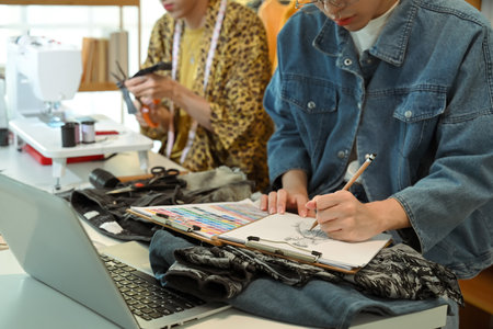 Fashion designers sketching and crafting new clothing designs in their studio.