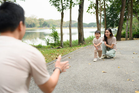 Excited little child running to father with open arms in the park.の写真素材