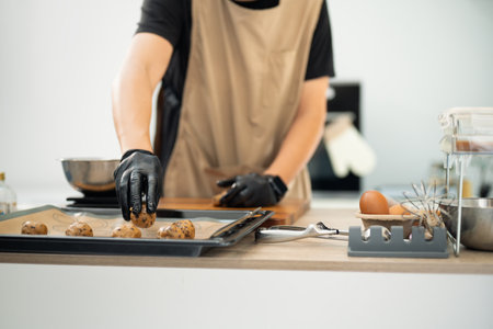 Close up of baker arranging cookie dough on a baking tray.の写真素材