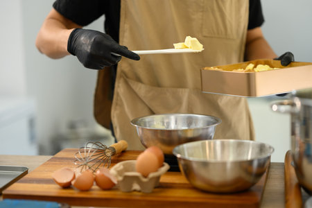 Cropped shot man adding butter to cookie dough mixture.