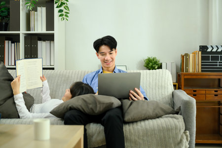 Relaxed young couple lounging on a cozy couch during leisure weekend time.の写真素材