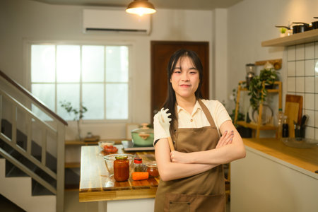 Confident woman standing proudly in her cozy kitchen, ready to cook a delicious spaghetti meal.の写真素材