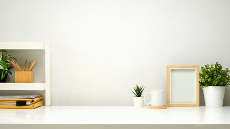 Minimalist workspace with small shelf, picture frame, cup of coffee and supplies.の写真素材