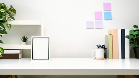 Minimalist workspace with small shelf, picture frame, cup of coffee and supplies.の写真素材