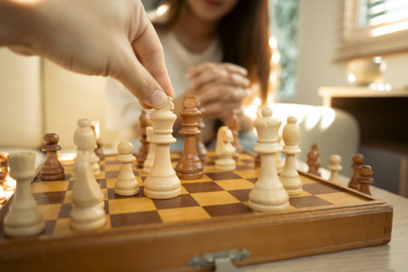 Close up of hand moves a chess piece on a classic wooden chessboard.の写真素材