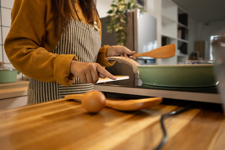 Young woman wearing striped apron preparing meal in a stylish modern kitchen.の写真素材