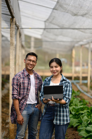 Confident farmers with digital tablet standing in organic farm. Smart farming concept.の写真素材