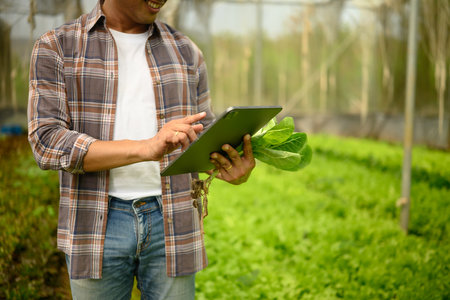 Smiling meal farmer using technology to assess crop quality inside a greenhouse. Smart farming...