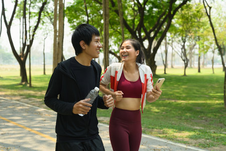 Happy young couple jogging together outdoors on a sunny day. Fitness and wellness concept.