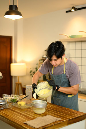 Man pouring freshly churned butter into strainer to separate buttermilk in a home kitchen.の写真素材