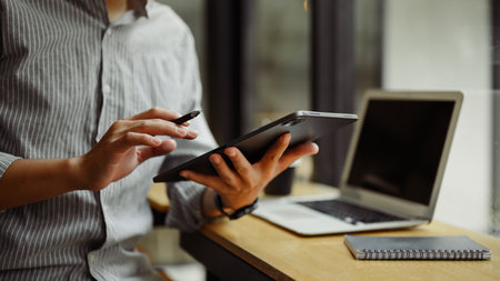 Young entrepreneur working with digital tablet and laptop at desk.の写真素材