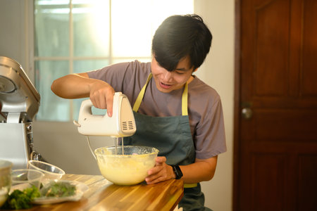 Man churning cream into butter with an electric mixer in a modern kitchen.